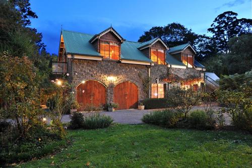 a large stone house with a large wooden garage at Mary Cards Coach House in Olinda