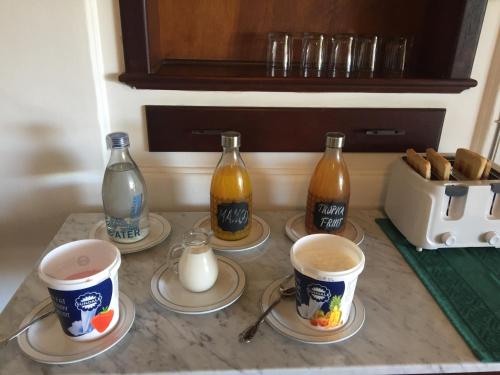 vier kopjes koffie op een aanrecht met flesjes en schoteltjes. bij Jackie's B&B in East London