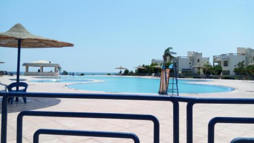 a view of a swimming pool with an umbrella at Two-Bedroom with Sea View Roof Top Chalet - Orora Village in Ain Sokhna