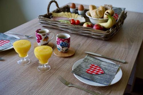 a table with a basket of fruit and glasses of orange juice at B & B De Gouwe Plek in Hoogwoud