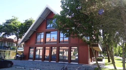 a red house with glass windows on a street at Rest Apartment Preila in Preila