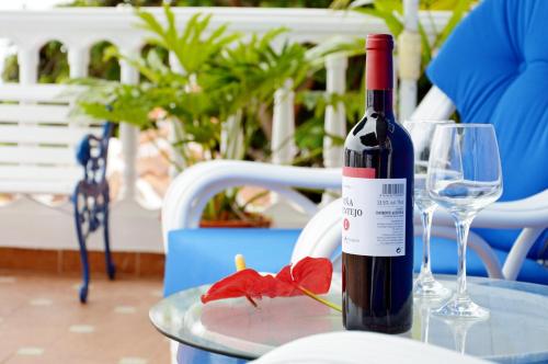 een fles wijn en een rode bloem op een tafel bij Hotel Drago San Antonio in Icod de los Vinos