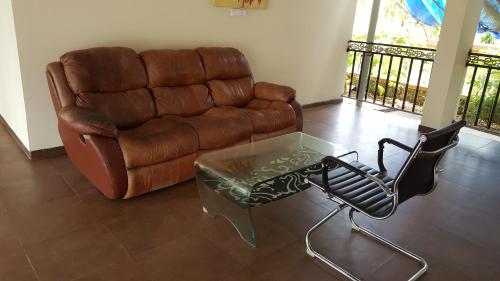 a living room with a couch and a glass coffee table at Anand Agro Tourism Kashid in Alibaug