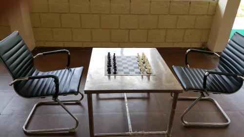 a chess board on a table with two chairs at Anand Agro Tourism Kashid in Alibaug