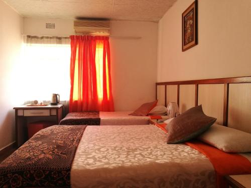 a hotel room with two beds and a window at Monica's Guesthouse in Welkom