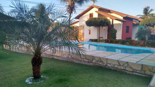 a palm tree in front of a house with a swimming pool at Chalés do Otto e Karine in Canoa Quebrada