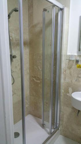 a shower with a glass door next to a sink at St George Hotel Great Yarmouth in Great Yarmouth