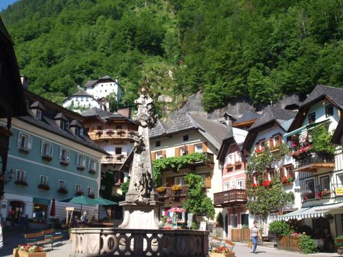 a statue in the middle of a town with houses at Haus Höll Herta in Hallstatt