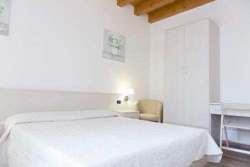 a white bedroom with a bed and a desk at Residence Eremitani in Padova