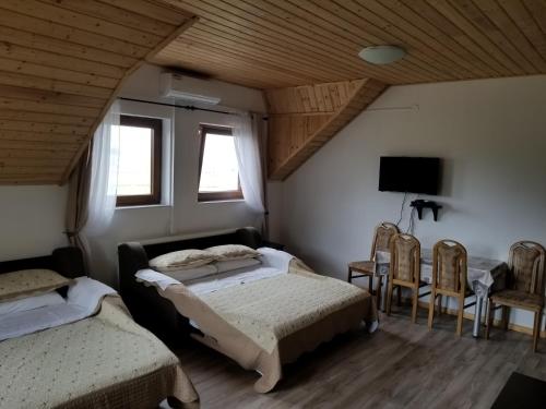 1 dormitorio con 2 camas, sillas y TV en Guest House Good Night, en Donji Babin Potok