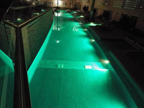 a swimming pool with green lights in a building at Puerta diamante acapulco in Acapulco