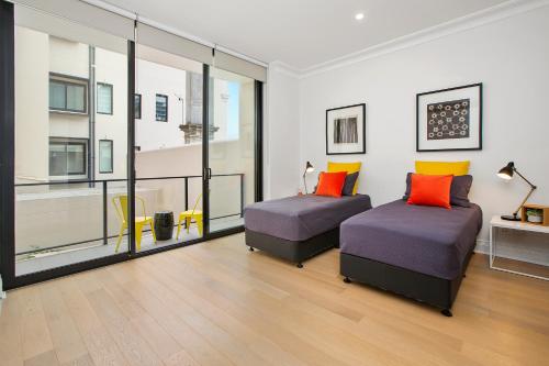 2 camas en una habitación con ventanas grandes en Orange Stay Apartments Potts Point, en Sídney