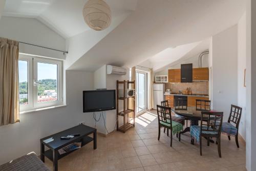 a living room with a table and chairs and a kitchen at Apartments Mazuran in Hvar