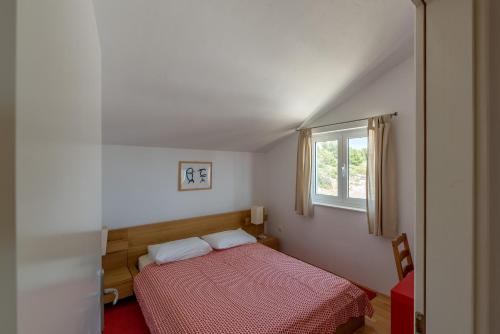 a small bedroom with a red bed and a window at Apartments Mazuran in Hvar
