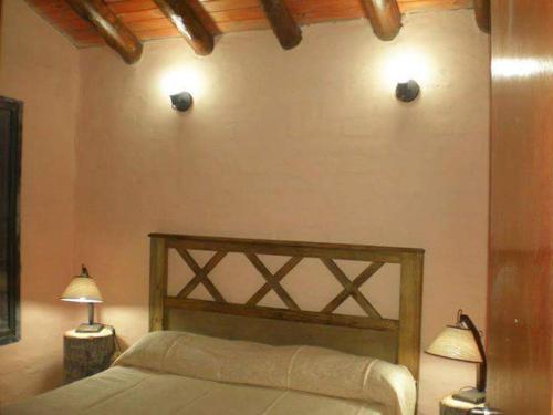 a bedroom with a bed with two lights on the wall at Cabaña Meralai in Potrerillos