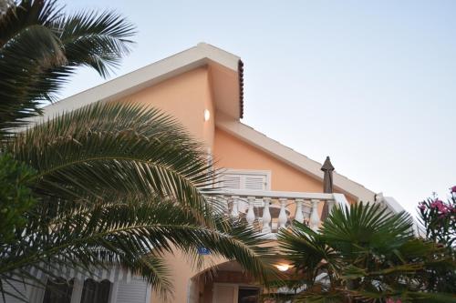 a house with a balcony and palm trees at Apartment Vujic in Vir