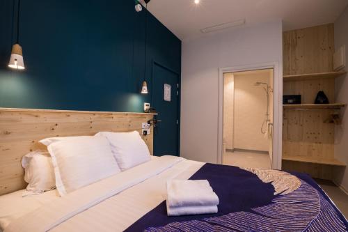 a bedroom with a large bed with a blue wall at Hôtel Café Miramar in Le Grau-du-Roi