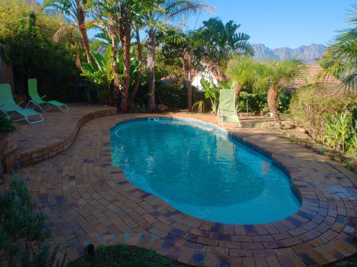 a swimming pool with chairs in a backyard at Swallow's Nest in Somerset West