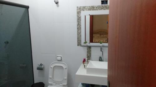 a bathroom with a toilet and a sink and a mirror at Casa em São Tomé das Letras in São Thomé das Letras