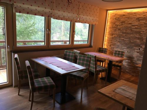 a dining room with two tables and chairs and windows at Apart Hotel Arno in Sölden
