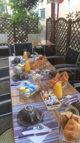 Una mesa con alimentos para el desayuno y jugo de naranja sobre ella. en Hotel des Remparts, en Villeneuve-sur-Lot