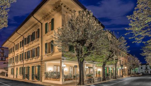 een groot gebouw met een boom ervoor bij Hotel Boston in Montecatini Terme