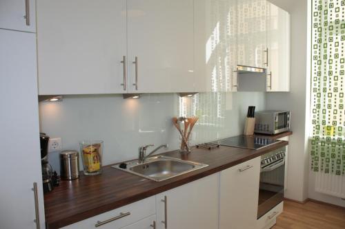 a kitchen with white cabinets and a sink at govienna - City Center Apartments in Vienna