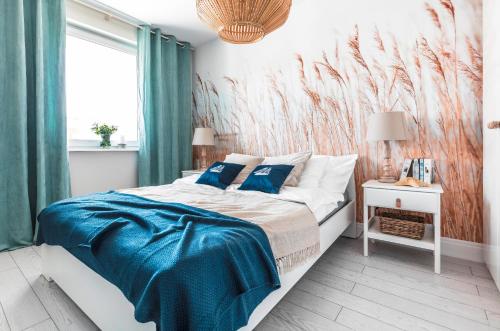 una camera da letto con un letto con lenzuola blu e un murale di Resort Apartamenty Klifowa Rewal 8 a Rewal