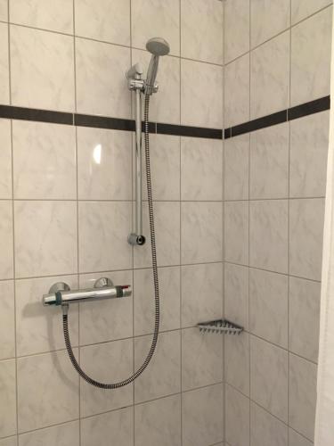 a shower with a shower head in a bathroom at Penny Pension in Wolfsburg