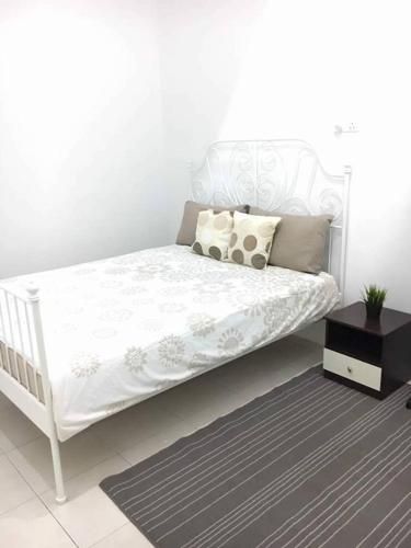 a white bed with pillows and a table in a room at Ceri Merah Homestay in Kuantan