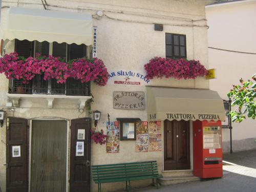 a building with flowers on the windows and a green bench at Bed & Breakfast "Il Ghiro" in San Martino sulla Marruccina