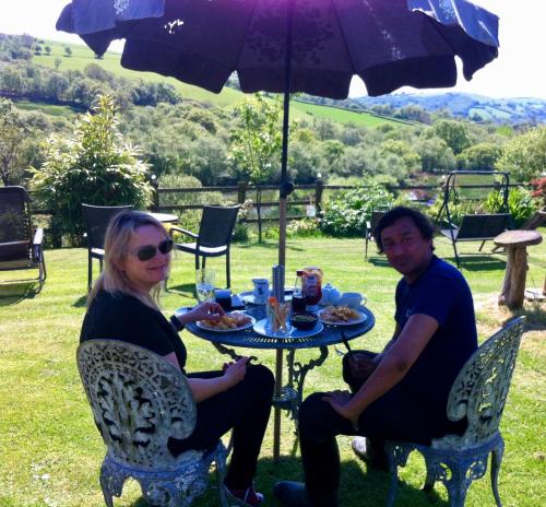a man and woman sitting at a table under an umbrella at Five Saints Farmhouse B&B in Pumpsaint