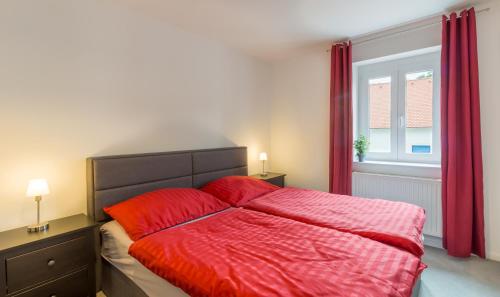 a bedroom with a bed with red sheets and a window at Gasthof Silberner Hirsch in Güssing