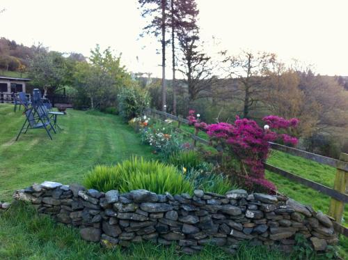 a garden with a stone wall and flowers at Five Saints Farmhouse B&B in Pumpsaint