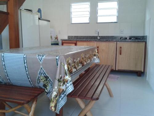 a kitchen with a table and a wooden bench at Casa de Temporada Farias in Palhoça