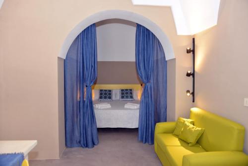 a room with an arch with a bed and a yellow couch at Dammusi SOLMAR in Pantelleria