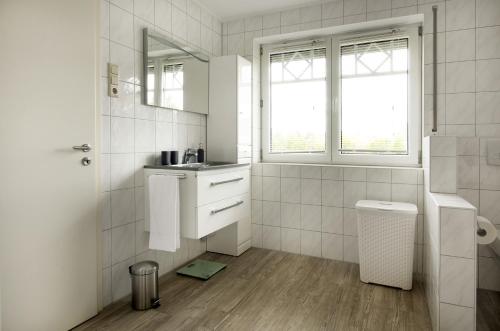 a white bathroom with a sink and a mirror at Luxury Apartment Kampe in Stemwede