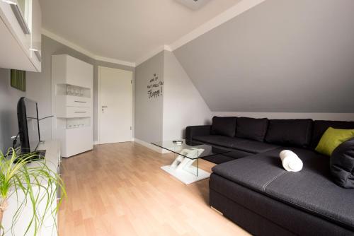 a living room with a black couch and a tv at Luxury Apartment Kampe in Stemwede
