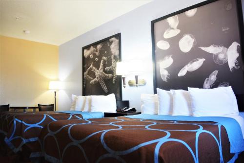 a hotel room with two beds with white pillows at Super 8 by Wyndham Galveston in Galveston
