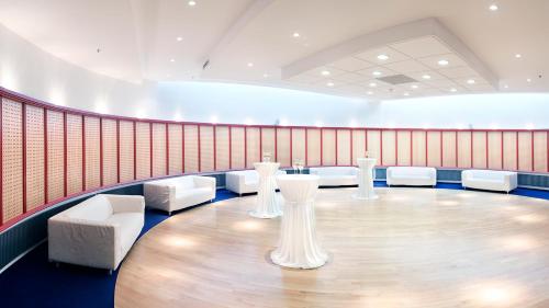a large room with a table and white chairs at Mercure Hotel Riesa Dresden Elbland in Riesa