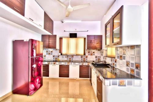 a kitchen with white cabinets and a red refrigerator at Rams Guest House Near Lulu Mall in Trivandrum