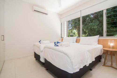 two beds in a bedroom with a large window at Pool Resort Port Douglas in Port Douglas
