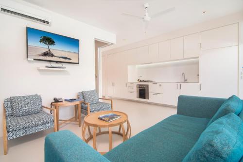 a living room with a blue couch and two chairs at Pool Resort Port Douglas in Port Douglas