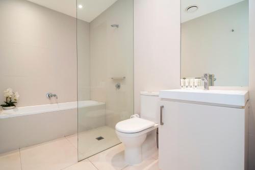 a white bathroom with a toilet and a sink at Pool Resort Port Douglas in Port Douglas