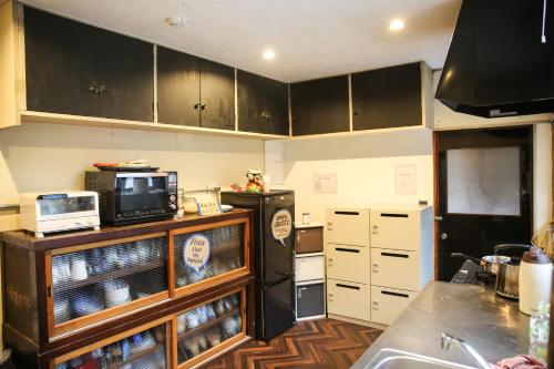 a kitchen with black cabinets and a microwave at Dot Hostel Nagano in Nagano