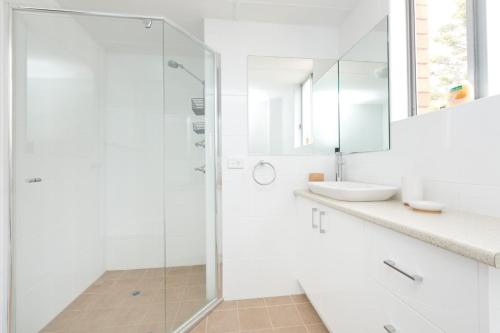 a white bathroom with a shower and a sink at Beachpoint Unit 501 in Forster