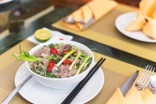 a bowl of food sitting on a table with chopsticks at Hanoi Golden Holiday Hotel in Hanoi