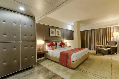 a hotel room with a bed and a chair at Quality Hotel D V Manor in Vijayawāda