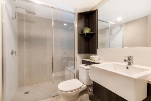 a bathroom with a toilet and a sink and a shower at Sunshine Tower Hotel in Cairns