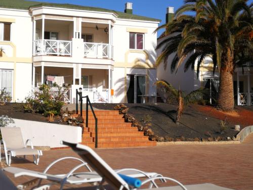 a white building with a palm tree and stairs at Piccola Oasi in Corralejo